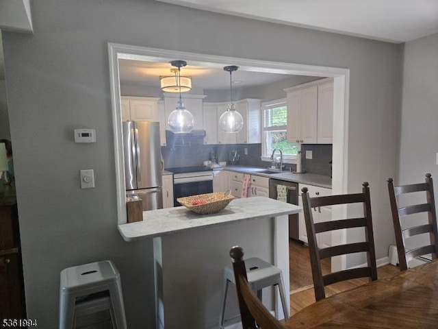 38 Weldon Rd, Jefferson Twp, NJ 07849 - kitchen featuring appliances with stainless steel finishes, a peninsula, white cabinetry, a breakfast bar, and tasteful backsplash