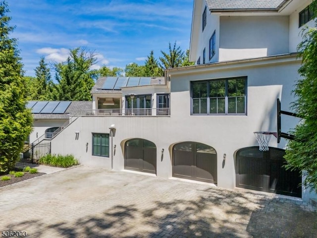 60 Fernwood Rd, Summit City, NJ 07901 - view of front of home with stucco siding, solar panels, a garage, a balcony, and decorative driveway