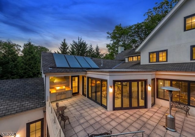 60 Fernwood Rd, Summit City, NJ 07901 - back of property at dusk with solar panels, stucco siding, a patio, and roof with shingles