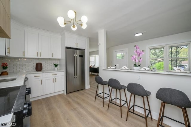 144 Elm St, Rockaway Twp, NJ 07801 - kitchen with high end fridge, a breakfast bar, white cabinets, and decorative backsplash