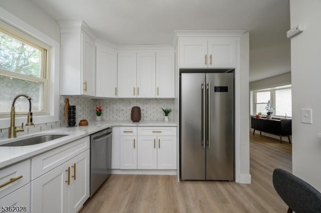 144 Elm St, Rockaway Twp, NJ 07801 - kitchen with stainless steel appliances, a sink, light wood-style floors, backsplash, and white cabinets