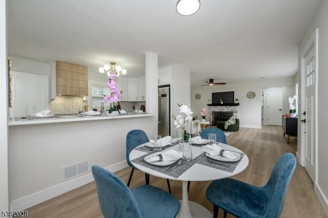 144 Elm St, Rockaway Twp, NJ 07801 - dining space with light wood-style floors, a brick fireplace, a ceiling fan, and baseboards