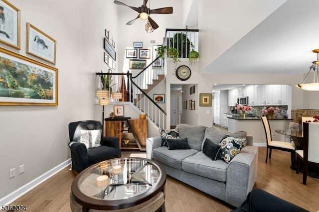 18 Inverrary Pl, Clinton Twp, NJ 08801 - living room featuring ceiling fan, stairs, a towering ceiling, wood finished floors, and baseboards