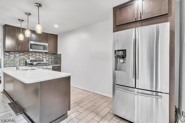 2200 Paterson Plank Rd Unit 23, North Bergen Twp, NJ 07047 - kitchen with appliances with stainless steel finishes, a sink, dark brown cabinets, decorative backsplash, and a peninsula
