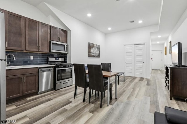 430 Ocean Ave, Jersey City, NJ 07305 - kitchen with stainless steel appliances, a sink, light wood-style floors, dark brown cabinets, and tasteful backsplash