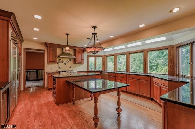 1 Willow Brook Ln, Clinton Twp, NJ 08801 - kitchen featuring recessed lighting, light wood-style floors, wall chimney range hood, dark stone counters, and brown cabinets