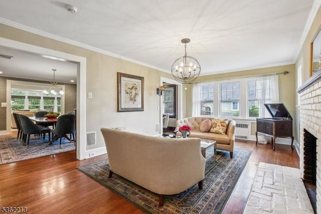 89 Maple St, Millburn Twp, NJ 07041 - living room featuring a chandelier, radiator heating unit, wood finished floors, crown molding, and a brick fireplace