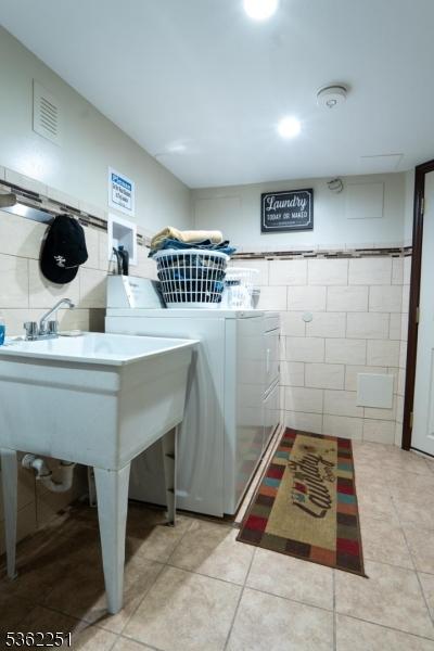 513 Maple Ave, Elizabeth City, NJ 07202 - laundry area with washing machine and clothes dryer, tile walls, and light tile patterned floors