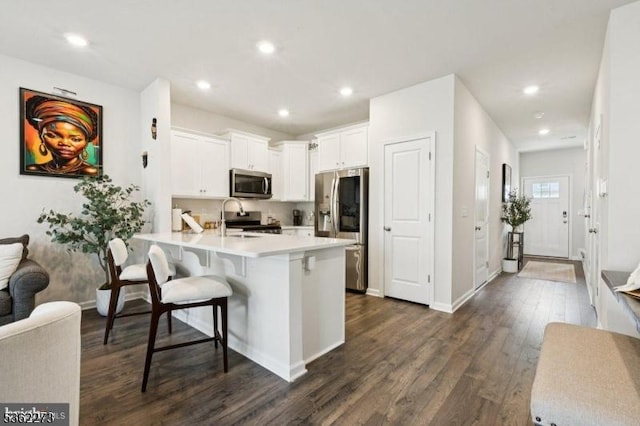 51 Peregrine Way, Burlington Twp, NJ 08016 - kitchen with appliances with stainless steel finishes, a peninsula, a breakfast bar area, dark wood-style floors, and white cabinets