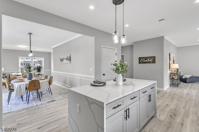 28 Kenmore Rd, Edison Twp, NJ 08817 - kitchen featuring crown molding, light stone countertops, light wood-type flooring, decorative light fixtures, and a center island