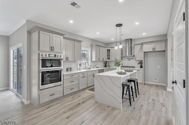 28 Kenmore Rd, Edison Twp, NJ 08817 - kitchen with wall chimney range hood, stainless steel double oven, gray cabinetry, a kitchen bar, and a kitchen island