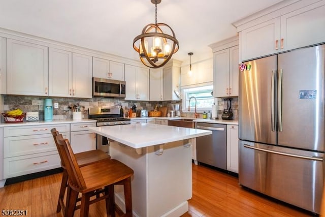 40 Riveredge Dr, Fairfield Twp, NJ 07004 - kitchen with appliances with stainless steel finishes, decorative backsplash, light wood finished floors, and a chandelier