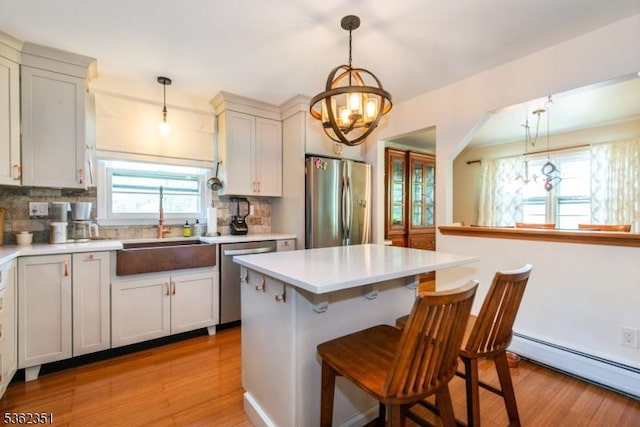 40 Riveredge Dr, Fairfield Twp, NJ 07004 - kitchen featuring stainless steel appliances, a baseboard heating unit, a sink, decorative backsplash, and a chandelier