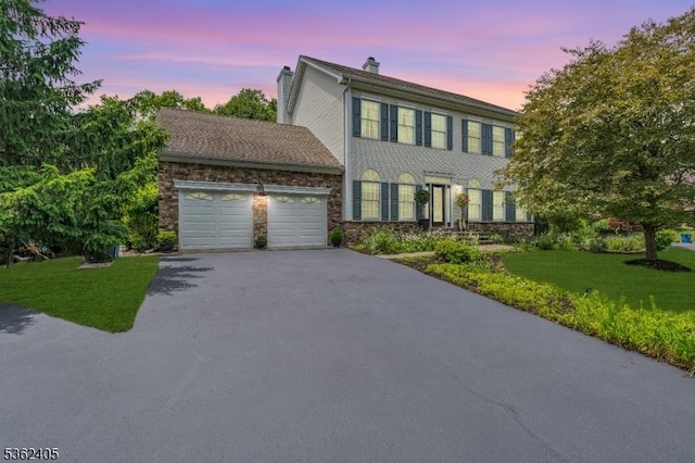 61 Bradley Ln, Bridgewater Twp, NJ 08807 - colonial house featuring an attached garage, driveway, a chimney, a lawn, and stone siding