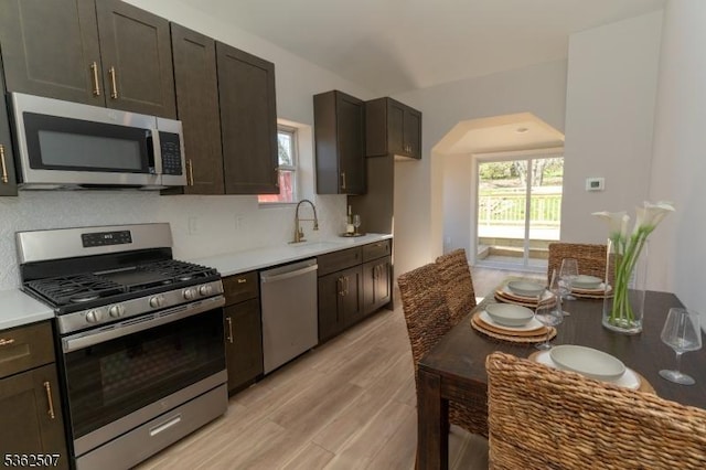 100 Cutters Dock Rd, Woodbridge Twp, NJ 07095 - kitchen featuring appliances with stainless steel finishes, tasteful backsplash, dark brown cabinets, light wood-style flooring, and a sink