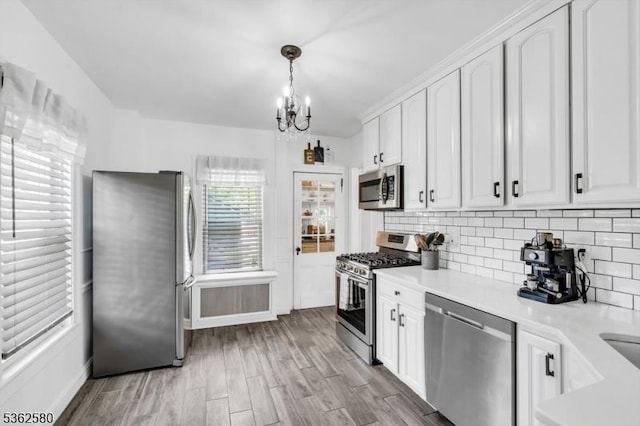 142 Westervelt Ave, North Plainfield Boro, NJ 07060 - kitchen featuring appliances with stainless steel finishes, a chandelier, white cabinetry, light wood-style flooring, and backsplash