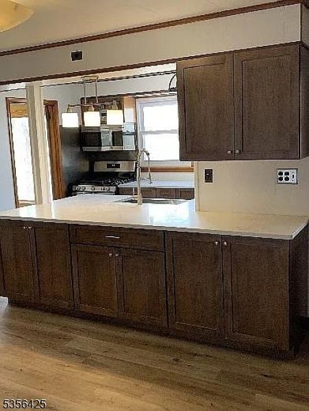297 Terhune Dr, Wayne Twp, NJ 07470 - kitchen featuring appliances with stainless steel finishes, wood finished floors, dark brown cabinets, light countertops, and crown molding