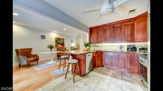 8 Clark Ct, Bernards Twp, NJ 07920 - kitchen with appliances with stainless steel finishes, decorative backsplash, light stone countertops, a peninsula, and ceiling fan