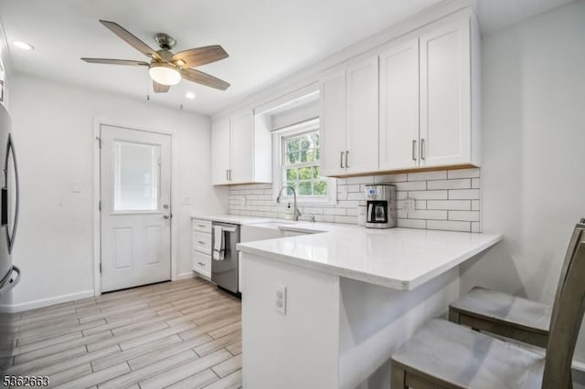 22 Corwin St, Randolph Twp, NJ 07869 - kitchen with stainless steel appliances, a peninsula, white cabinetry, backsplash, and light countertops