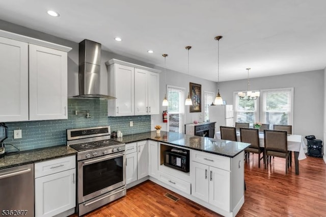 146 Williamson Ave, Hillside Twp, NJ 07205 - kitchen featuring stainless steel appliances, wall chimney range hood, a peninsula, a chandelier, and white cabinets