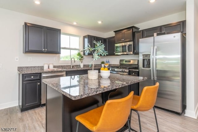 49 Coventry Rd, Hardyston Twp, NJ 07419 - kitchen featuring appliances with stainless steel finishes, dark stone countertops, light wood-style flooring, a breakfast bar area, and a center island