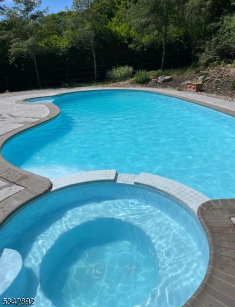 522 Stanhope Rd, Byram Twp, NJ 07871 - view of pool featuring a pool with connected hot tub and view of wooded area