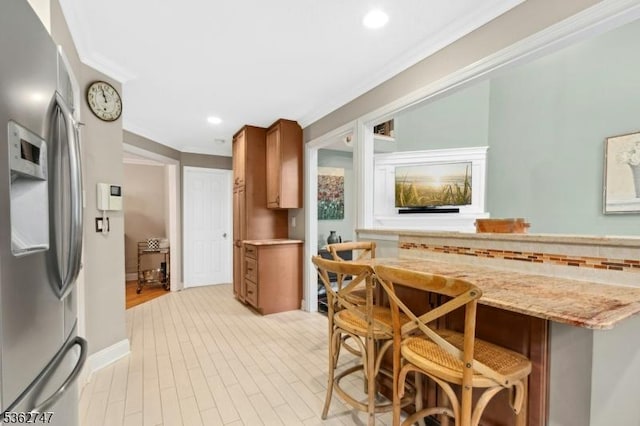 3607 Park Pl, Springfield Twp, NJ 07081 - kitchen with stainless steel fridge, a breakfast bar area, brown cabinets, recessed lighting, and light stone countertops