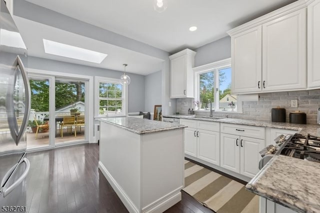 30 Hillcrest Ter, Verona Twp, NJ 07044 - kitchen with appliances with stainless steel finishes, a skylight, white cabinetry, a center island, and decorative backsplash