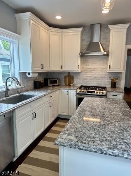 30 Hillcrest Ter, Verona Twp, NJ 07044 - kitchen with wall chimney exhaust hood, appliances with stainless steel finishes, white cabinets, decorative backsplash, and light stone countertops