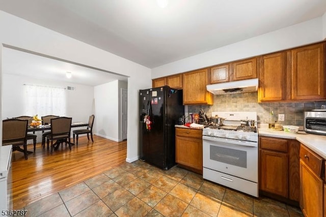 303-305 W Runyon St, Newark City, NJ 07108 - kitchen featuring gas range gas stove, under cabinet range hood, black fridge with ice dispenser, and brown cabinetry