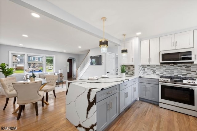 501 E 2nd Ave, Roselle Boro, NJ 07203 - kitchen with stainless steel gas range, gray cabinetry, white microwave, open floor plan, and decorative backsplash
