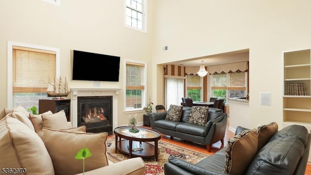 9 Independence Ct, Franklin Twp, NJ 08873 - living room with a glass covered fireplace, a high ceiling, built in shelves, a chandelier, and wood finished floors
