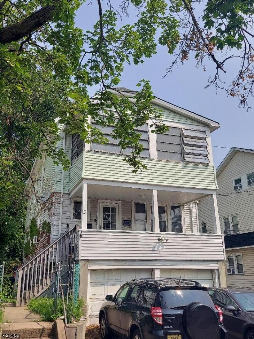 8 N 12th St, Hawthorne Boro, NJ 07506 - view of front of house with an attached garage, a balcony, and stairs
