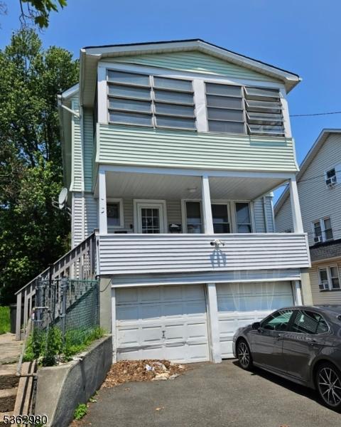 8 N 12th St, Hawthorne Boro, NJ 07506 - view of front facade featuring a balcony, a garage, and asphalt driveway