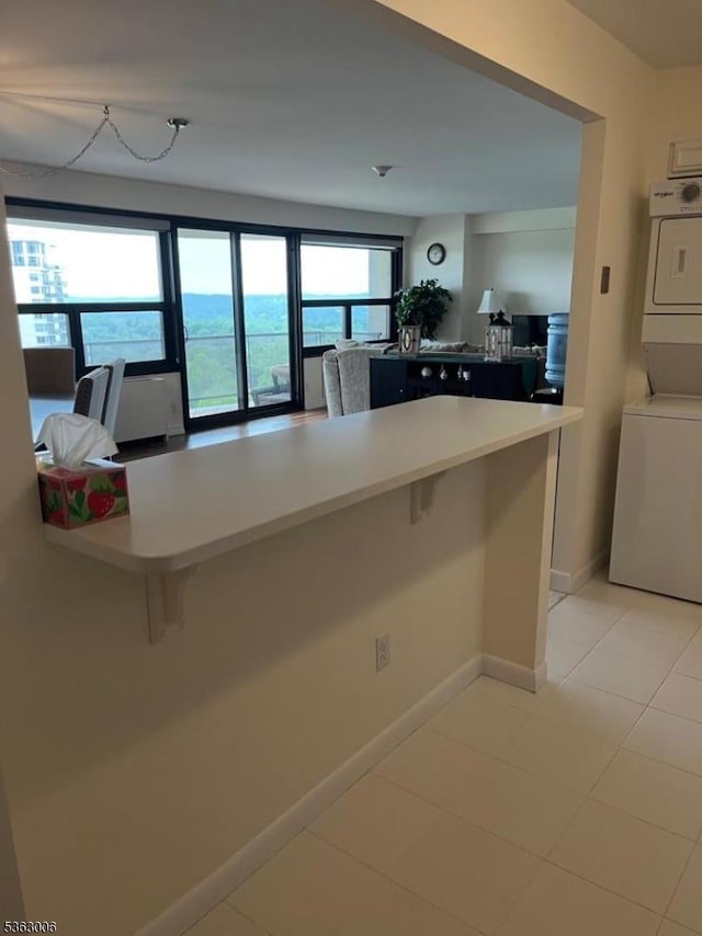 2 Claridge Dr Unit 7Ie, Verona Twp, NJ 07044 - kitchen with stacked washer / dryer, a breakfast bar, light countertops, and light tile patterned floors