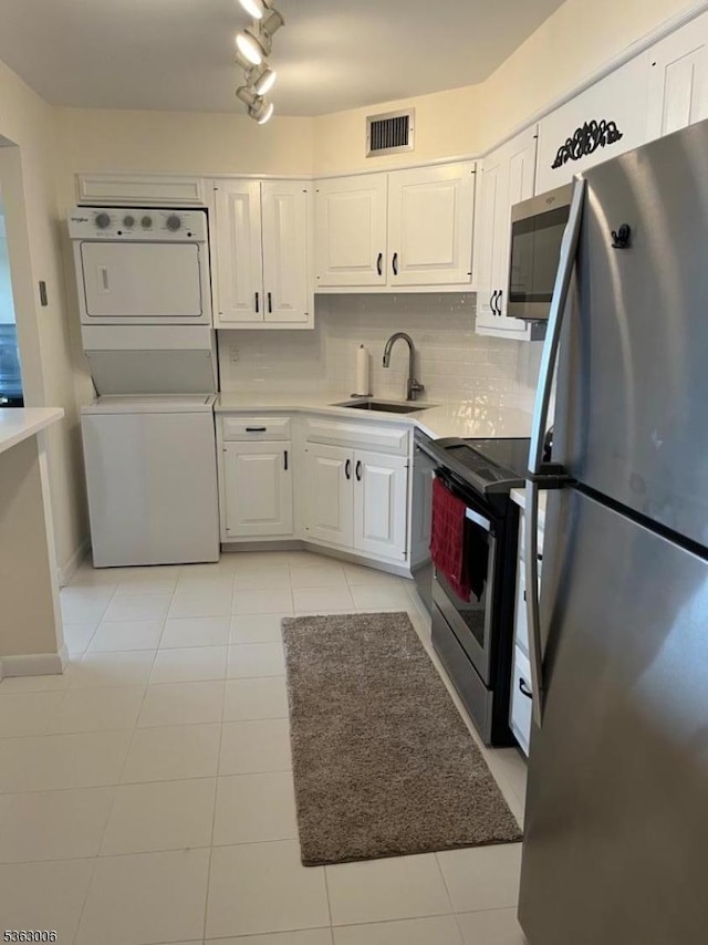 2 Claridge Dr Unit 7Ie, Verona Twp, NJ 07044 - kitchen featuring stainless steel appliances, stacked washer and clothes dryer, white cabinetry, and light tile patterned flooring