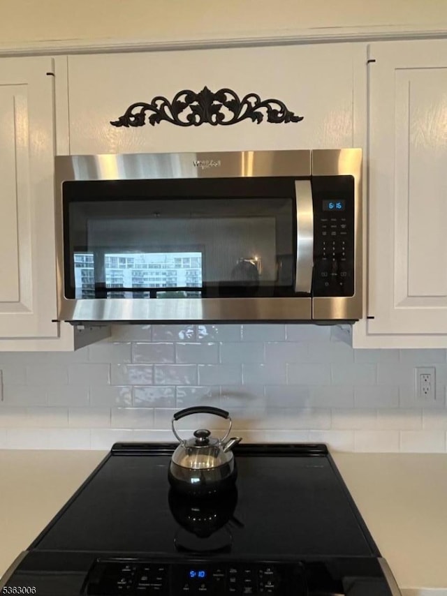 2 Claridge Dr Unit 7Ie, Verona Twp, NJ 07044 - kitchen view of stainless steel microwave, black / electric stove, white cabinetry, and backsplash