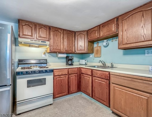 177 Schooleys Mountain Rd, Washington Twp, NJ 07853 - kitchen featuring under cabinet range hood, white gas range oven, brown cabinets, and freestanding refrigerator