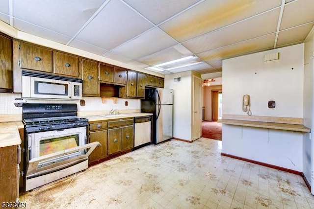 902E Merritt Dr, Hillsborough Twp, NJ 08844 - kitchen featuring stainless steel appliances, light countertops, a sink, and brown cabinets