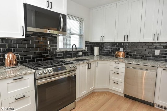 11-06 Marshall Rd, Fair Lawn Boro, NJ 07410 - kitchen featuring appliances with stainless steel finishes, white cabinetry, light wood finished floors, and light stone counters