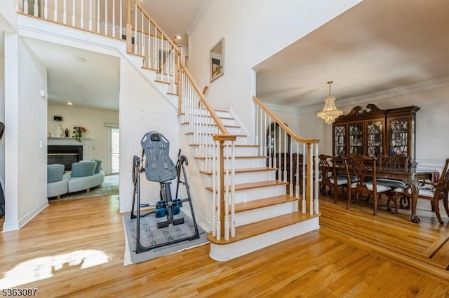 42 Stephens Mill Rd, Mount Olive Twp, NJ 07840 - stairs featuring wood finished floors, a chandelier, crown molding, a high ceiling, and a glass covered fireplace