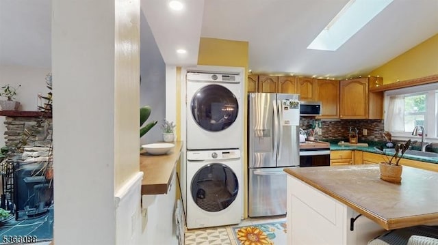 970 Cedar Dr, Stillwater Twp, NJ 07860 - kitchen featuring appliances with stainless steel finishes, stacked washer and clothes dryer, a skylight, backsplash, and lofted ceiling