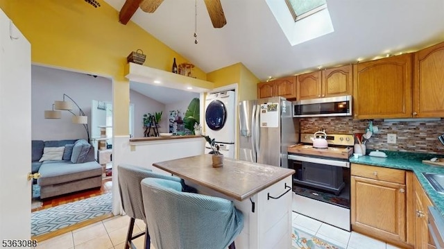 970 Cedar Dr, Stillwater Twp, NJ 07860 - kitchen with stainless steel appliances, stacked washer and clothes dryer, light tile patterned floors, lofted ceiling, and tasteful backsplash