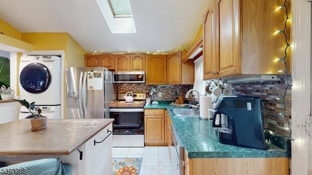 970 Cedar Dr, Stillwater Twp, NJ 07860 - kitchen with stainless steel appliances, a sink, stacked washing machine and dryer, tasteful backsplash, and a skylight