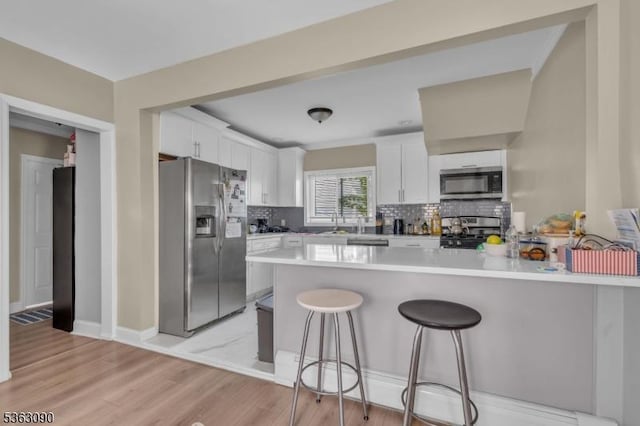 451 Centre St, Nutley Twp, NJ 07110 - kitchen with appliances with stainless steel finishes, a peninsula, decorative backsplash, and a kitchen bar