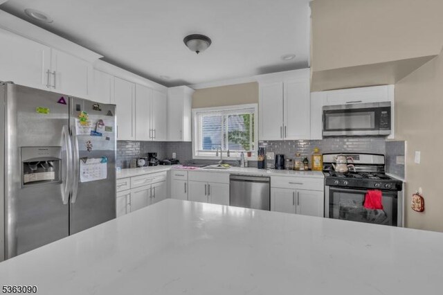 451 Centre St, Nutley Twp, NJ 07110 - kitchen with stainless steel appliances, light countertops, backsplash, white cabinetry, and a sink