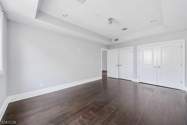 69 Summit Rd, Elizabeth City, NJ 07208 - unfurnished bedroom with a tray ceiling, baseboards, multiple closets, and dark wood finished floors