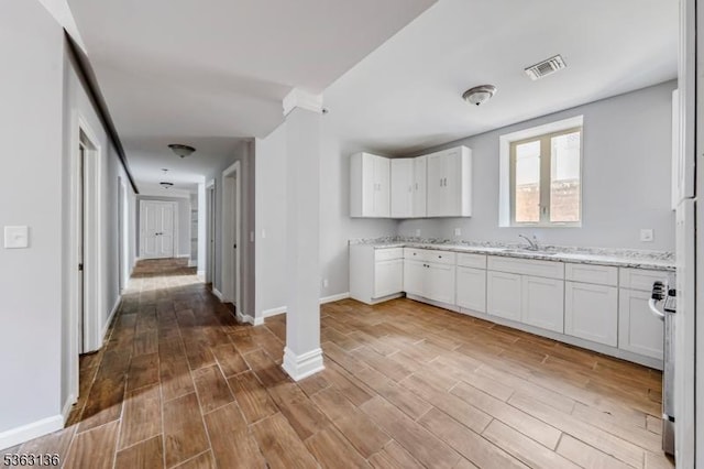 69 Summit Rd, Elizabeth City, NJ 07208 - kitchen with a sink, white cabinetry, wood finished floors, light stone countertops, and baseboards