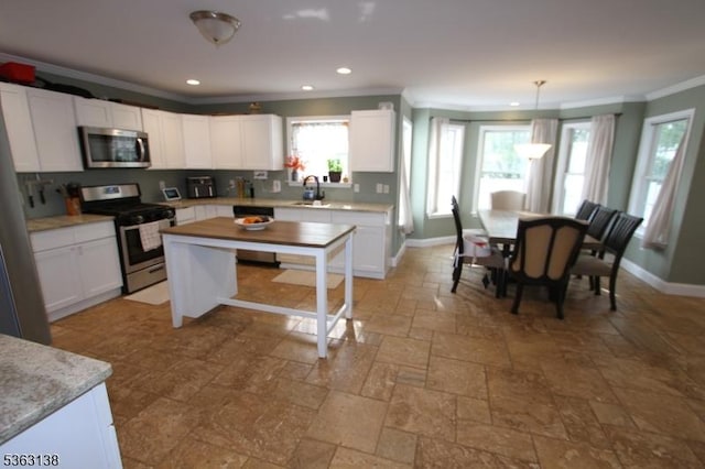 132 Sloop Rd, Stafford Twp, NJ 08050 - kitchen with stainless steel appliances, crown molding, a sink, stone tile flooring, and white cabinets