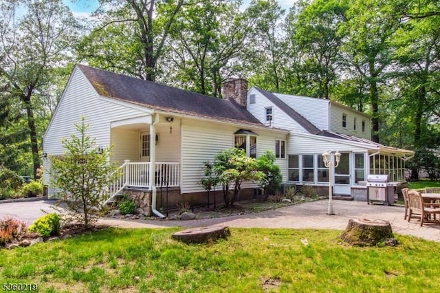 504 Pepperidge Tree Ln, Kinnelon Boro, NJ 07405 - rear view of property with a sunroom, a chimney, a patio area, a lawn, and a shingled roof